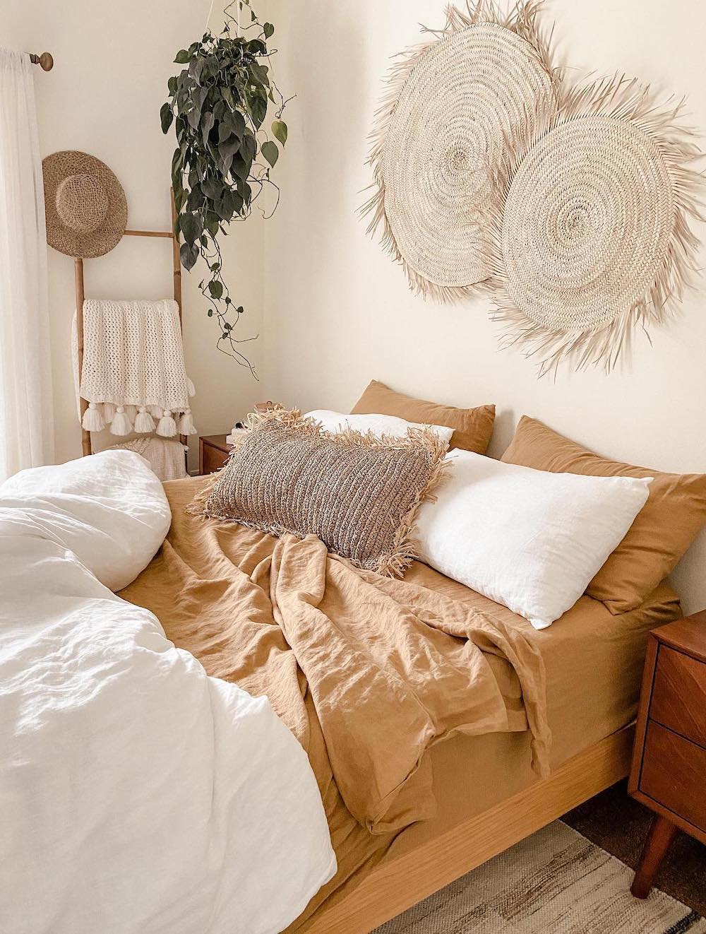 a boho bedroom with soft orange linens, wall baskets, and real plants