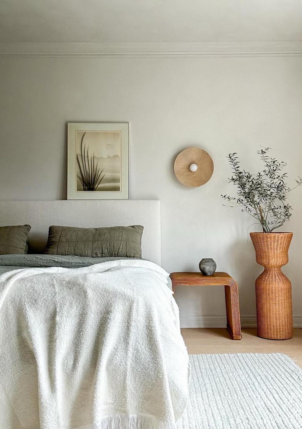 a boho bedroom featuring dark green and creamy tones with raffia decor and a minimalistic design