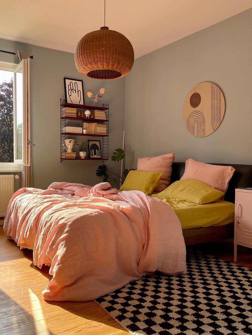 a bohemian bedroom with retro accents, a checkerboard rug, and pink and yellow linens
