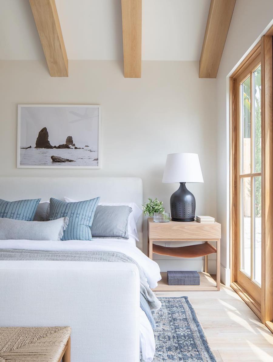 a coastal-themed bedroom with wooden beams on the ceiling and blue and ivory colors