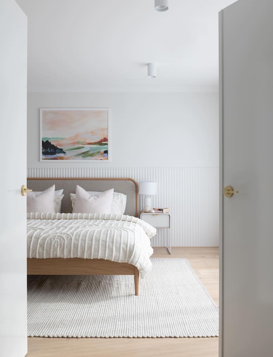 a white minimalist coastal bedroom with a colorful wall print