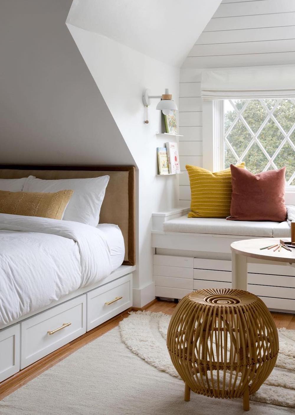 a small bedroom with pops of color and a window seat book nook