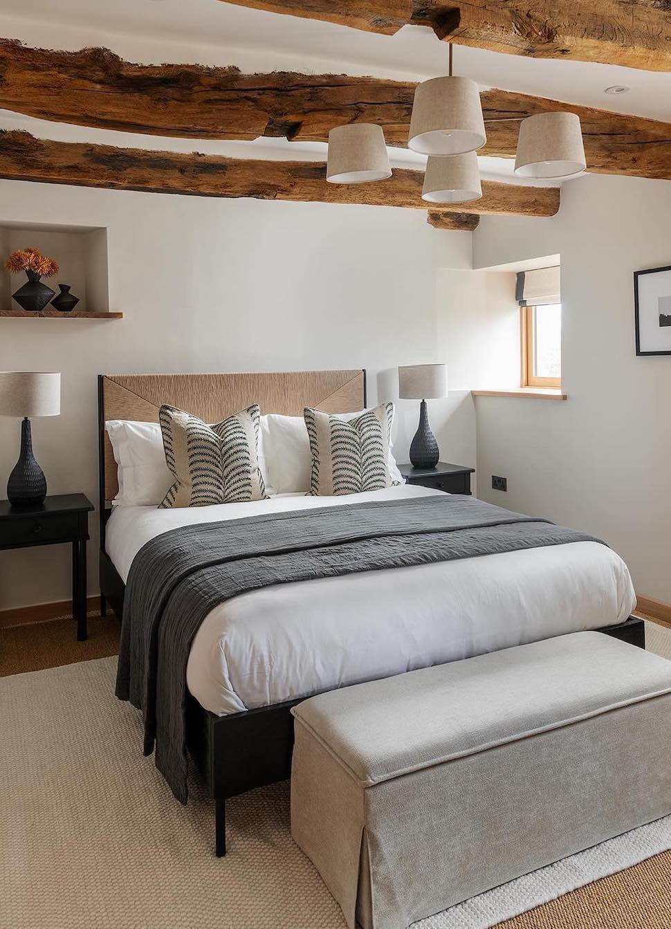 a bedroom with wooden beams, charcoal and white bedding, and modern decor