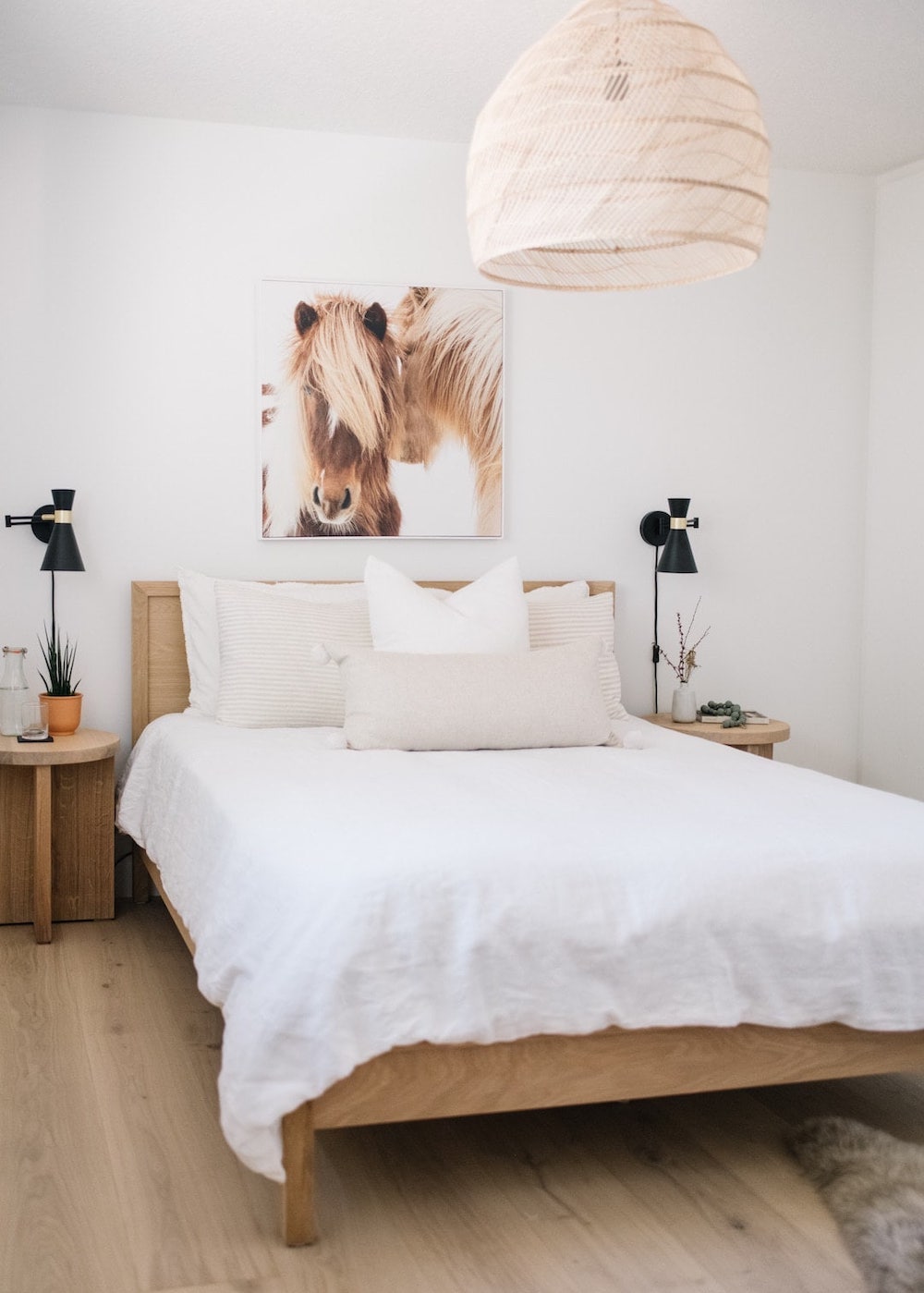 a white bedroom with animal art prints, rattan fixtures, and warm tones