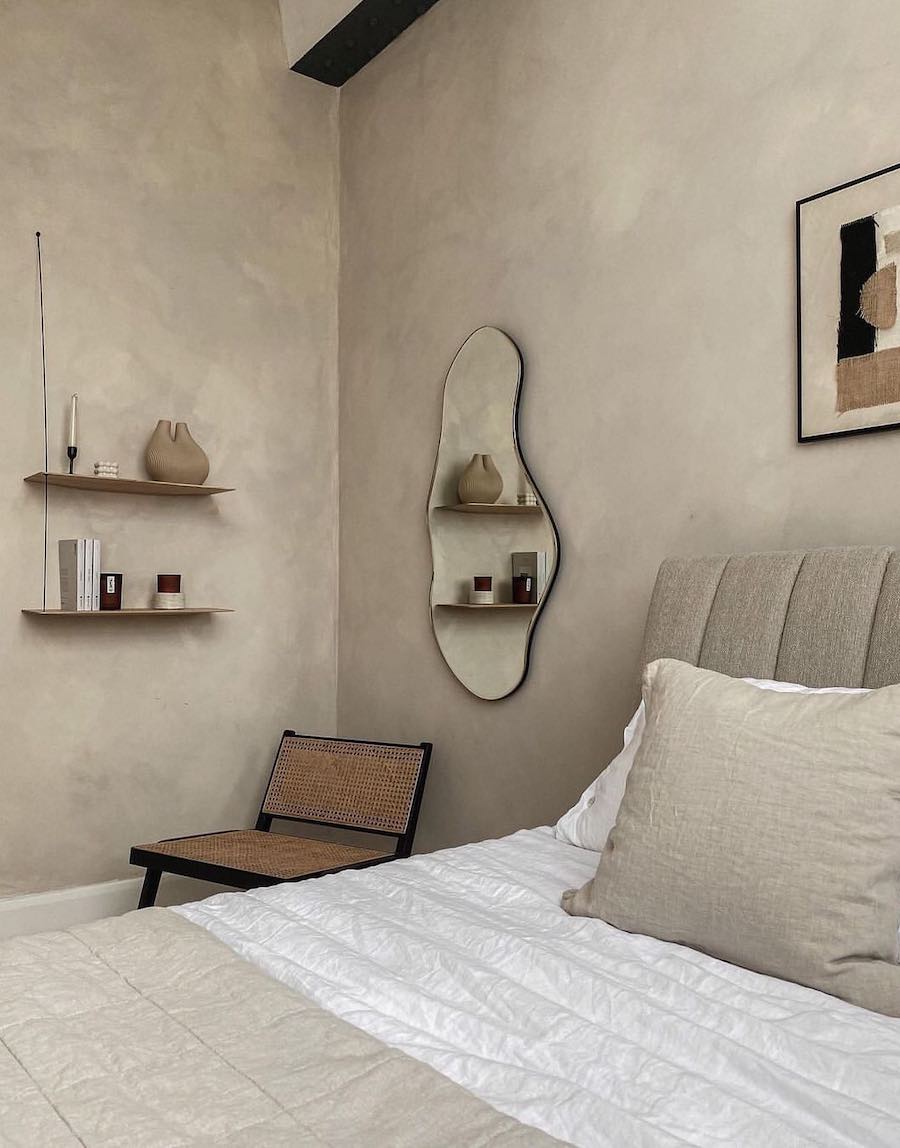 an organic modern bedroom featuring limewashed walls, simple and unique decor, and soft grey tones