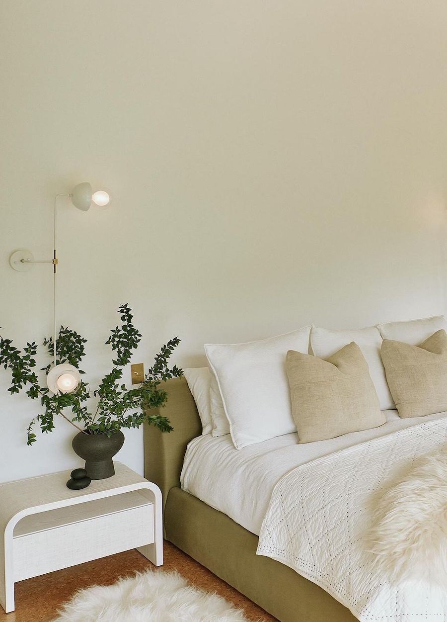 an organic modern bedroom featuring ecru tones, houseplants, and cozy bedding