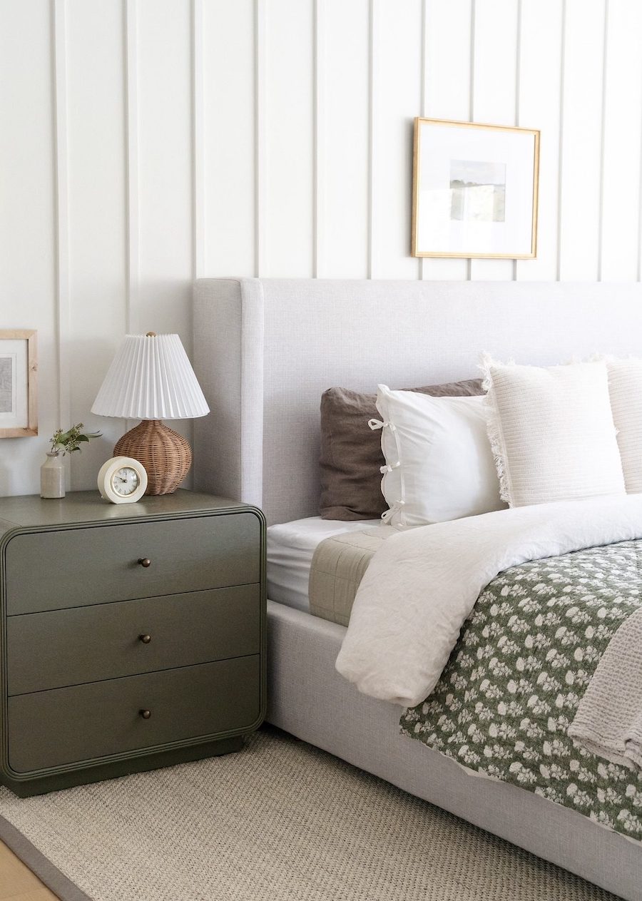 a bright white room with sage green bedding and furniture