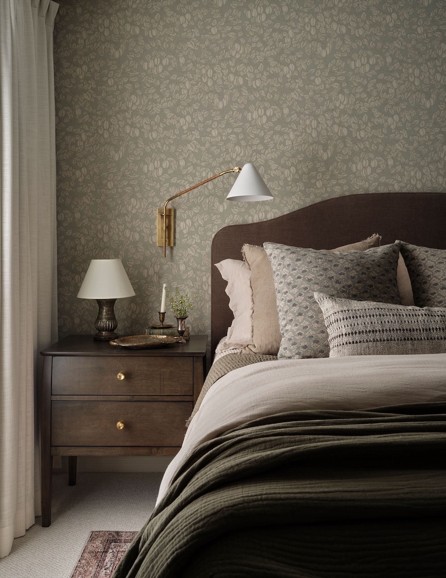 sage green floral wallpaper behind a moody vintage bed and nightstand