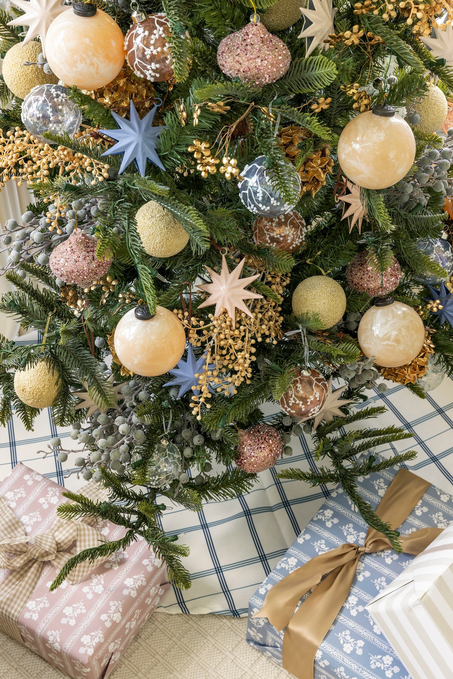 a christmas tree with marbled ornaments, star ornaments, and golden berries