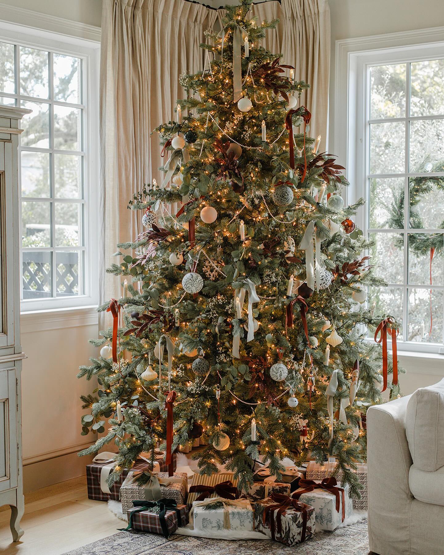 a christmas tree with traditional decor including pearl garland, bows, and ornaments