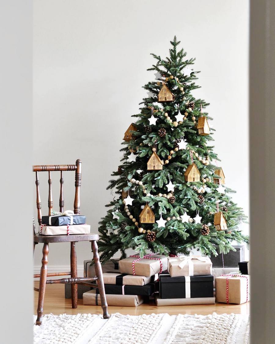 a christmas tree with wooden house ornaments, wooden bead garland, and star ornaments