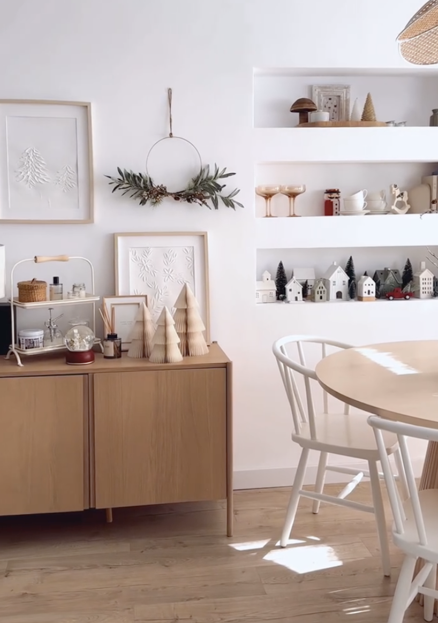 a dining room featuring indoor christmas decor including wooden trees, a minimalist wreath, and ceramic village decor