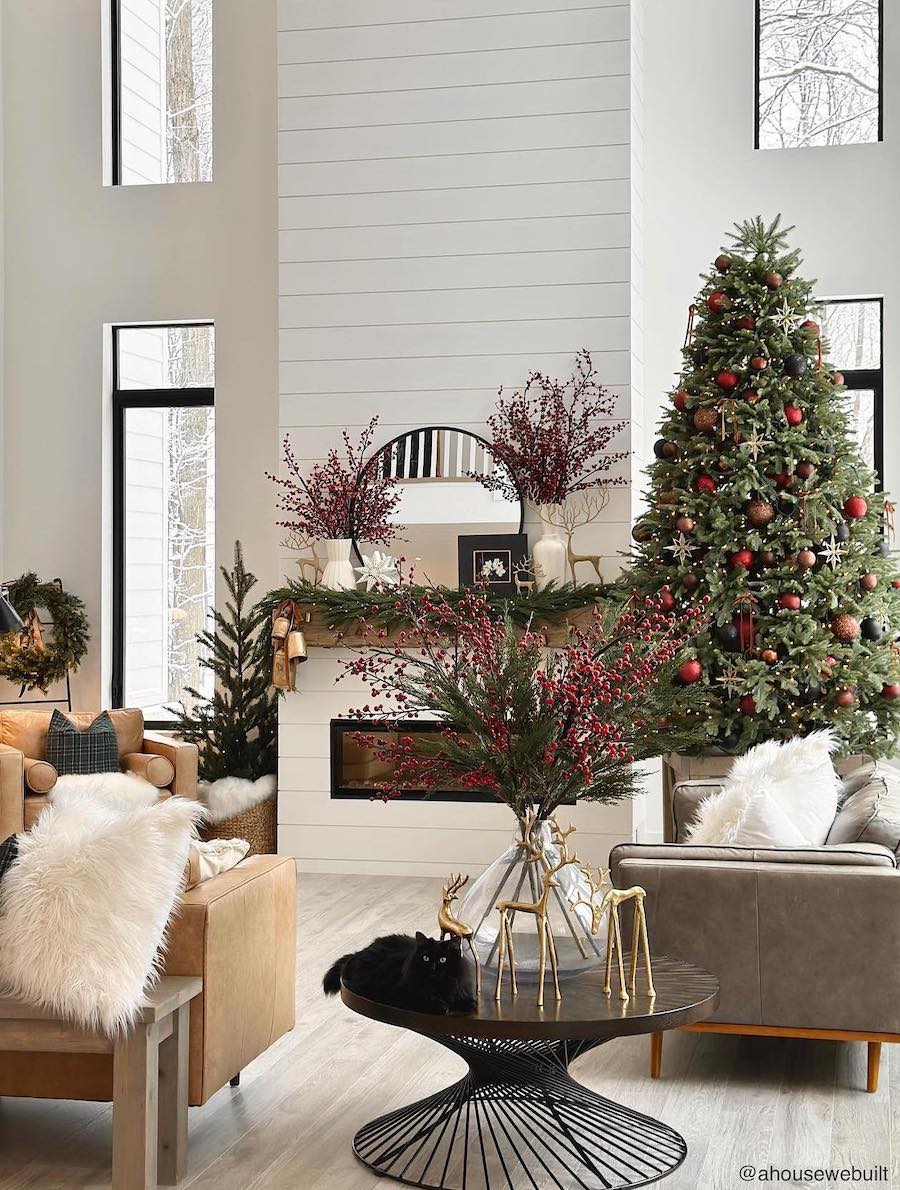 a living room featuring a christmas tree, golden reindeer, and pine and holly berry decor