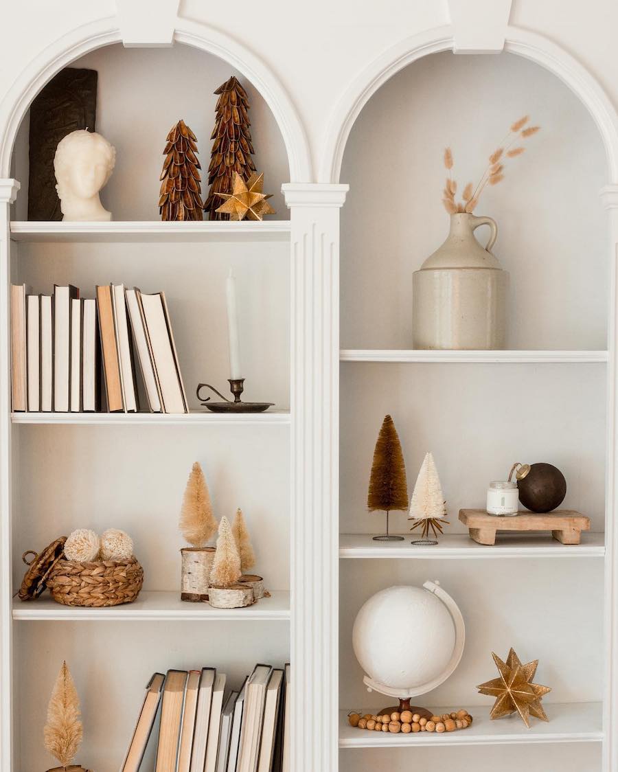 built-in shelves featuring small bottle brush christmas trees, golden stars and other neutral christmas decor