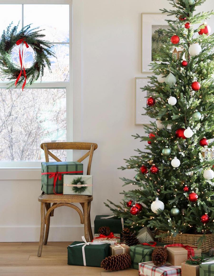 a christmas tree with white, red, and green ornaments with presents and wreaths around it