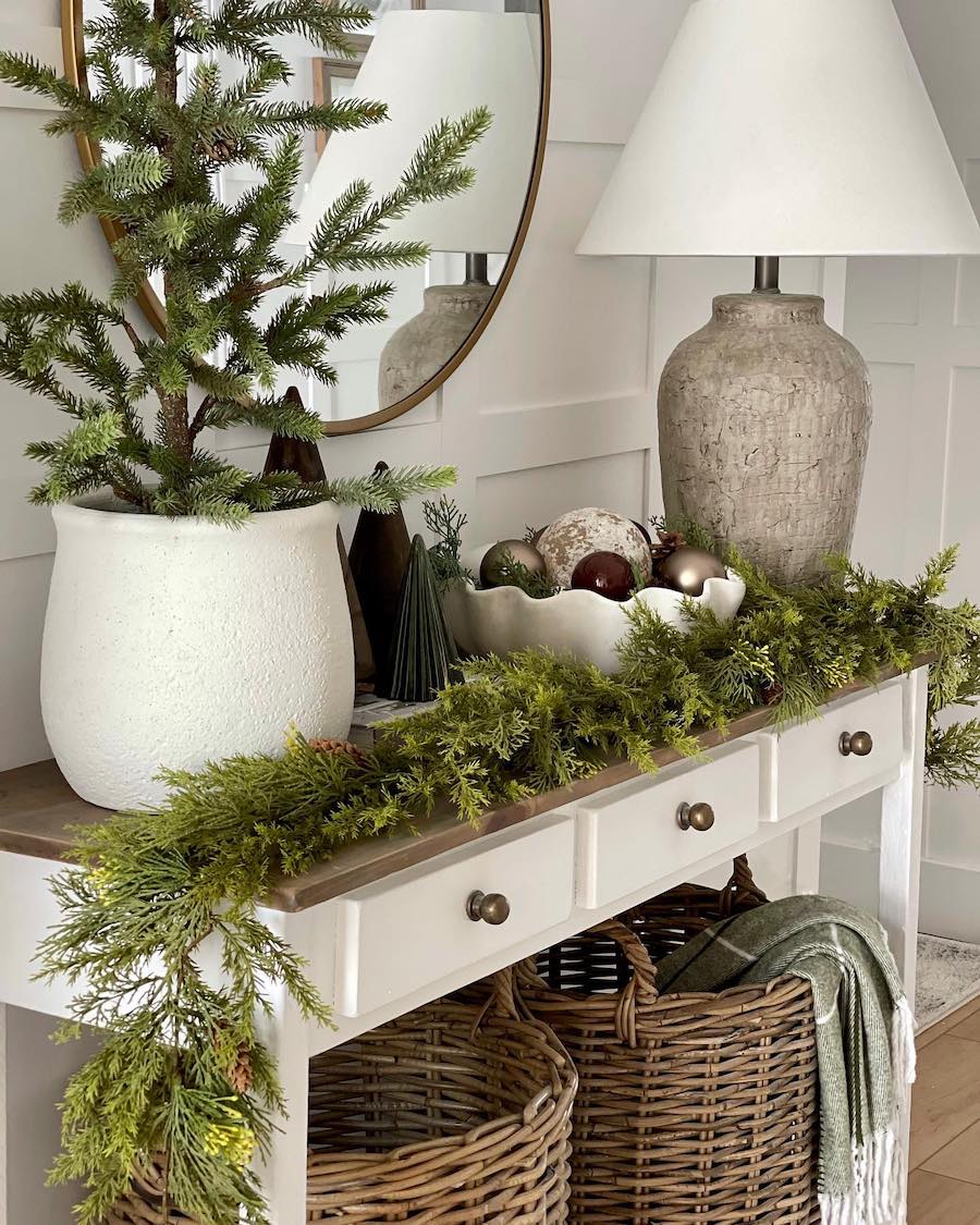 an entryway table with pine, tree, and ornament decor