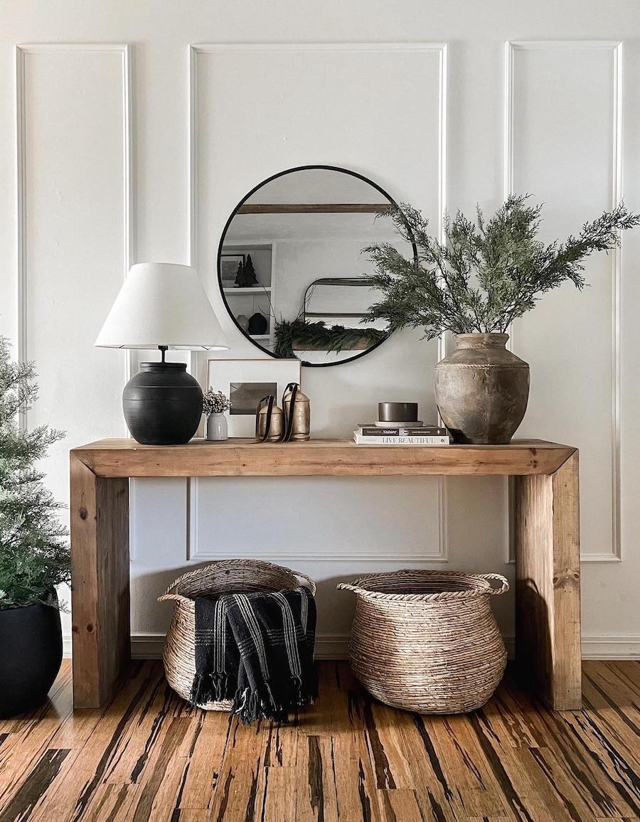 an entryway table with pine, golden bells, and plaid throw blankets