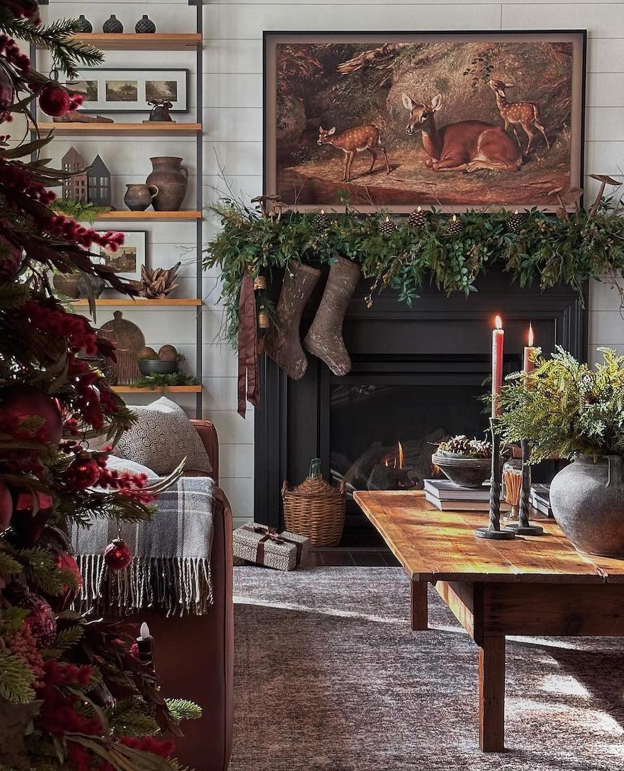 a living room with a woodland winter theme including candles, stockings, a christmas tree, and fall foliage