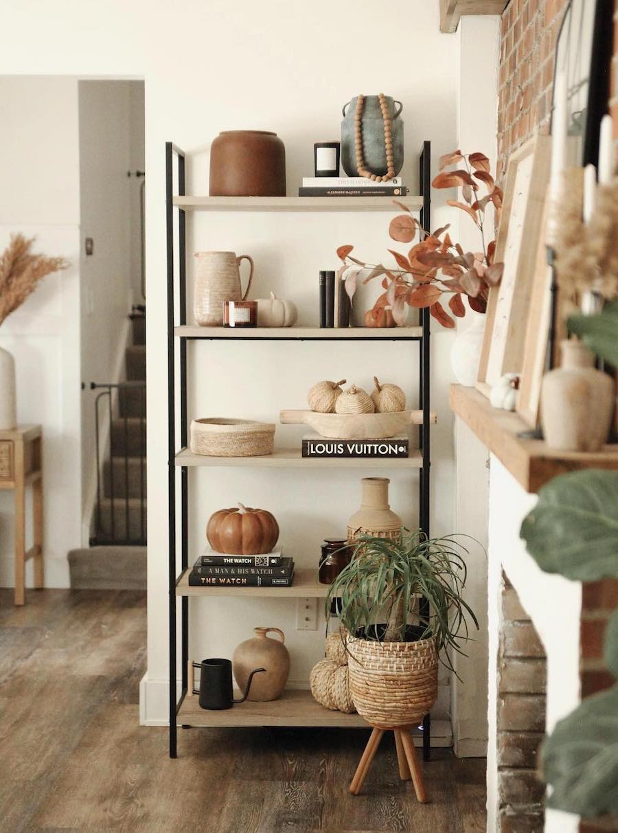 a living room shelf featuring pumpkins, vases with fall palettes, and other autumn decor