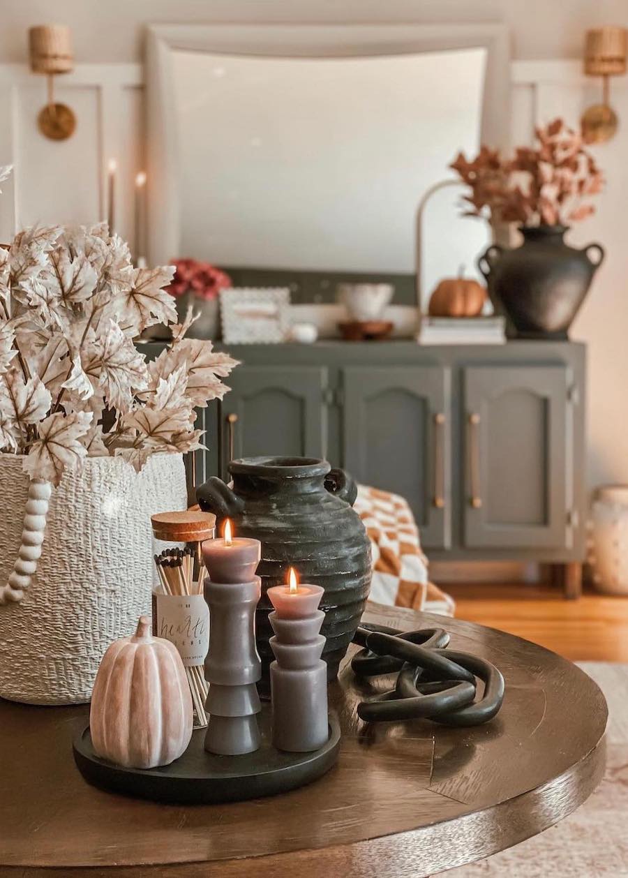 a living room featuring fall foliage, pumpkins, and candles as autumn decor