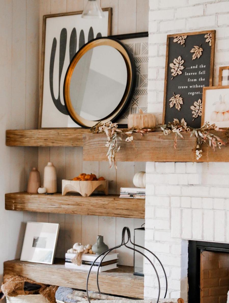 a wooden mantle and open wood shelves featuring fall foliage, fall signs, and pumpkin accents