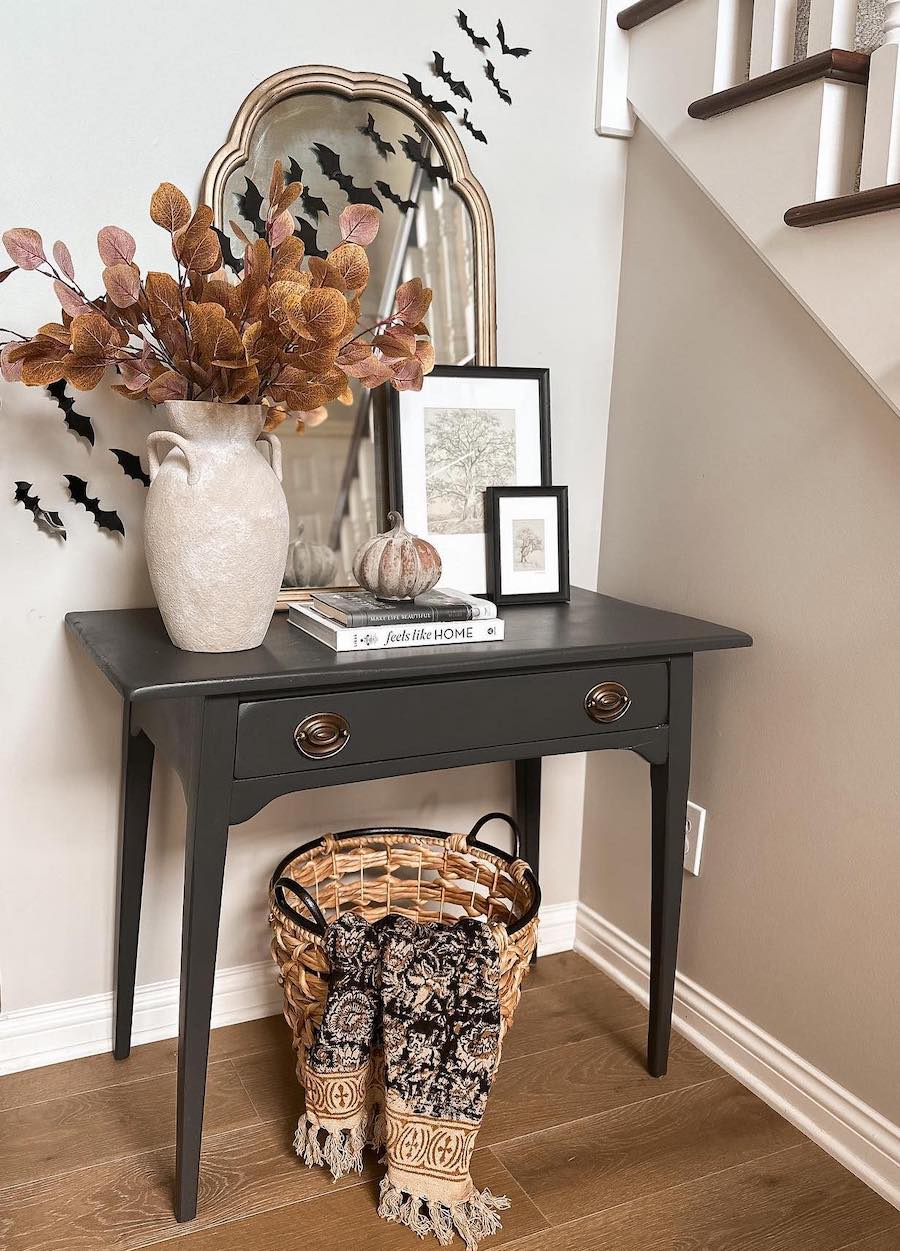 pumpkins, fall foliage bouquets, and paper bats on an entryway table