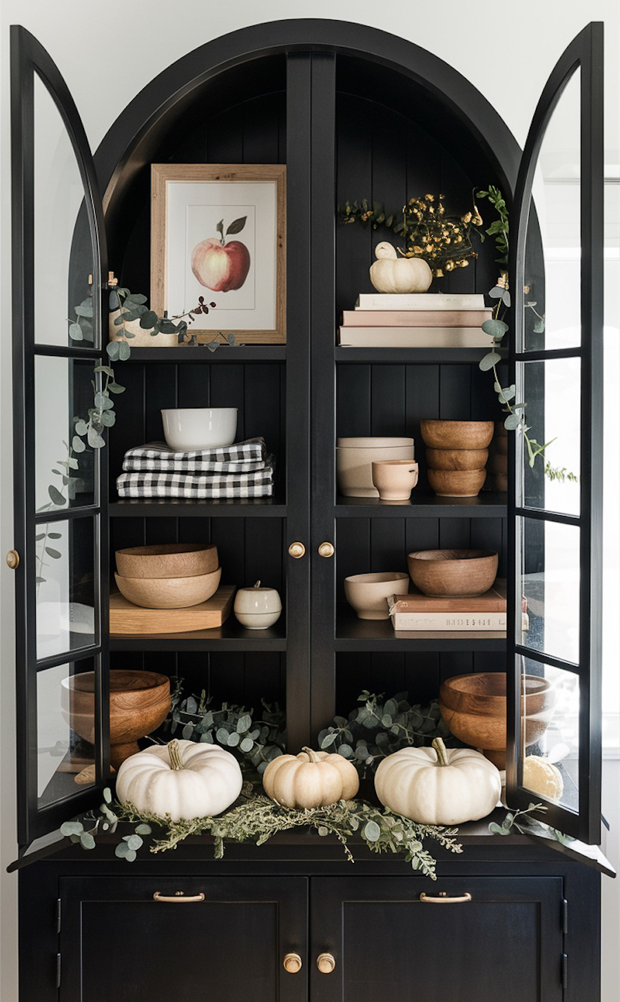 a black hutch featuring pumpkins, fall foliage, and wooden bowls