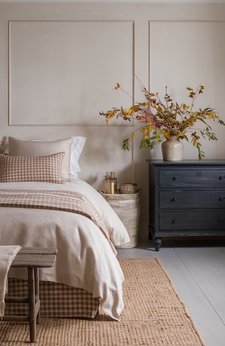 a bedroom featuring neutral plaid bedding and a fall floral arrangement