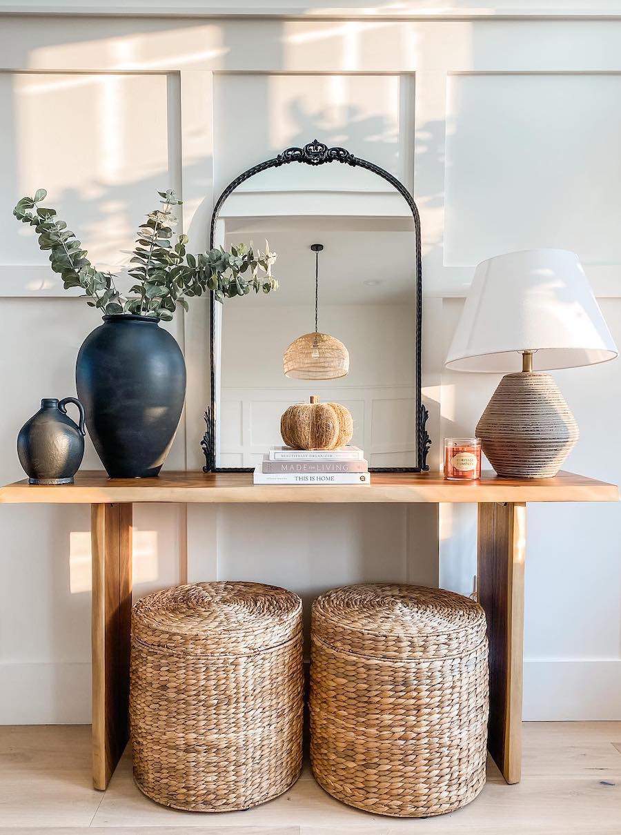 an entryway table featuring wicker, sleek decor, and simple pumpkin accents