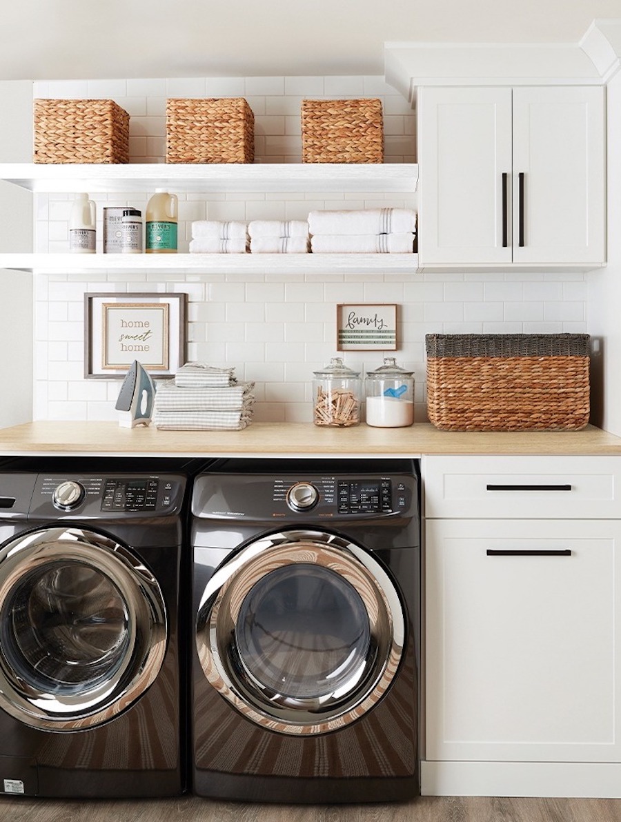 a laundry room featuring wooden counters, cabinets, and shelves above the machines