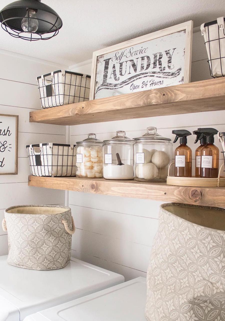 a laundry room with wooden shelves featuring baskets and glass canisters for organization