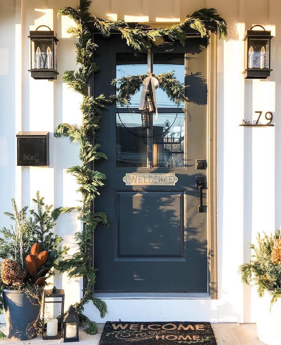 a front porch with pine decor, bows, and lanterns