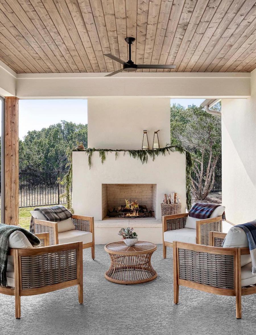 a back patio with plaid throw blankets over chairs, a fireplace, and pine garland