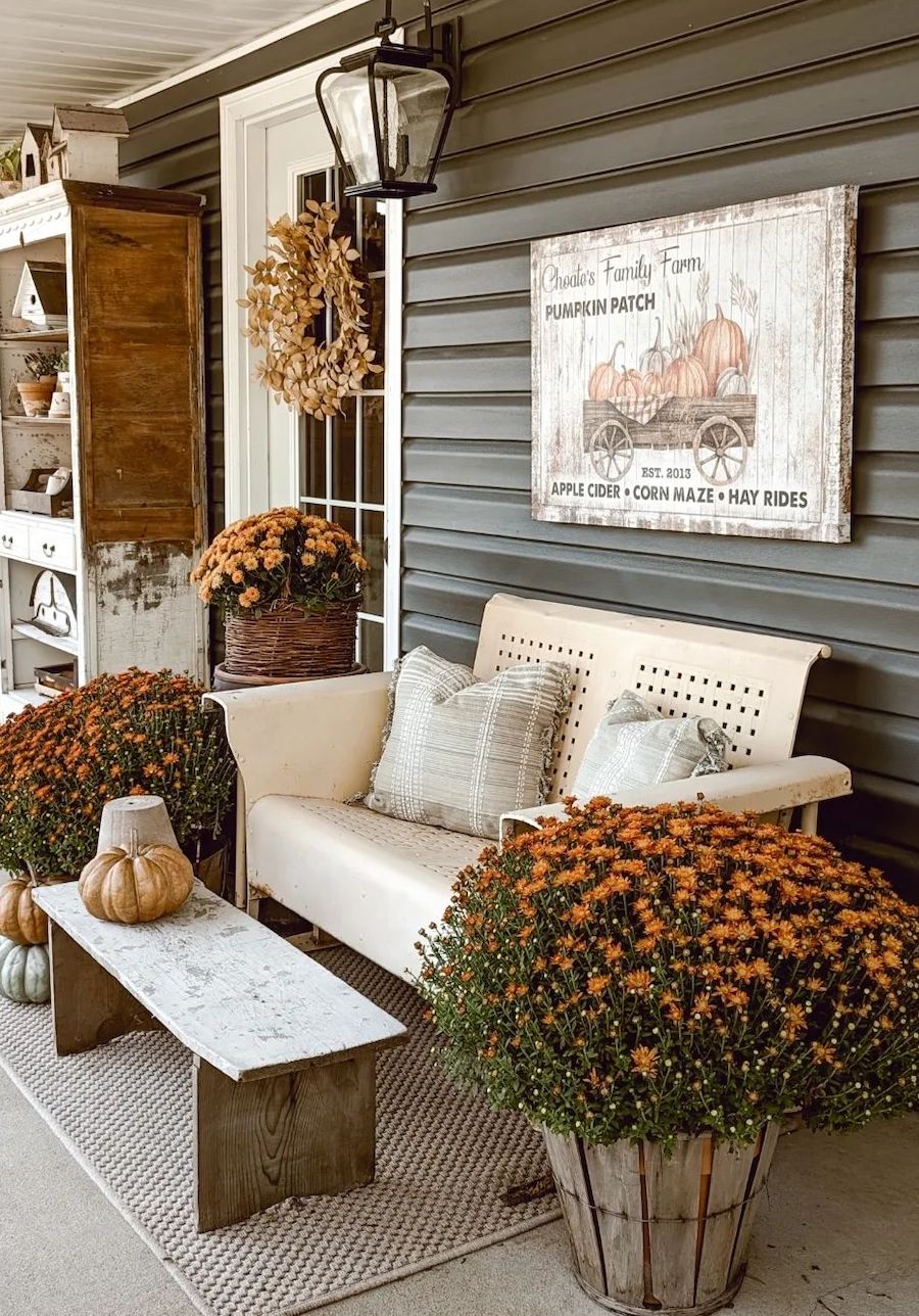 a farmhouse front porch with farmhouse signs, fall florals, pumpkins, and autumn-inspired wreaths