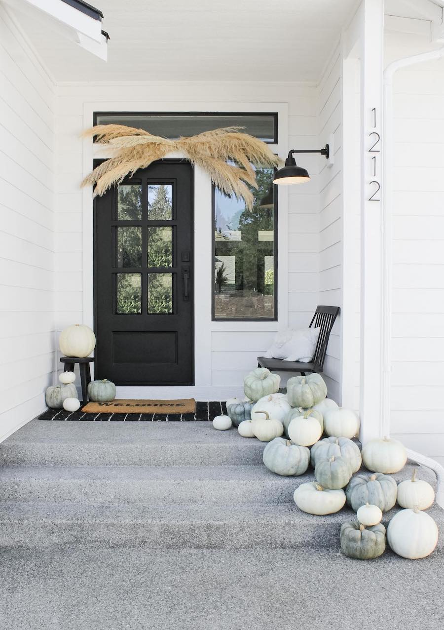 a front door porch with white and blue pumpkins