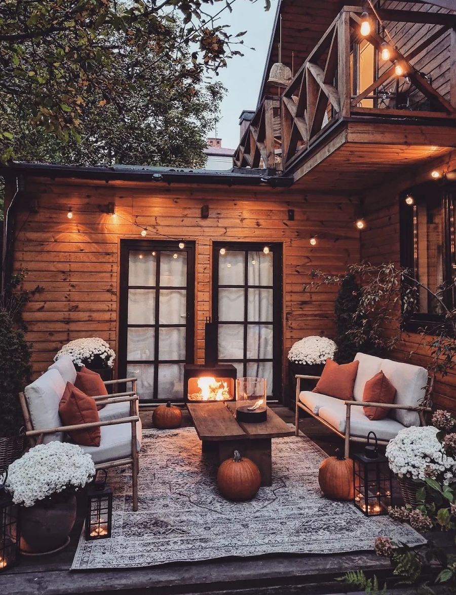 a back porch with pumpkins, white florals, and other cozy decor