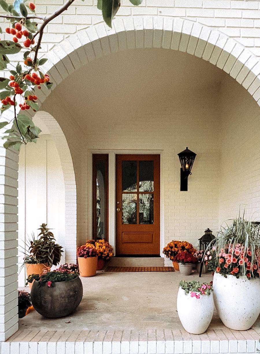 a front porch with fall floral arrangements