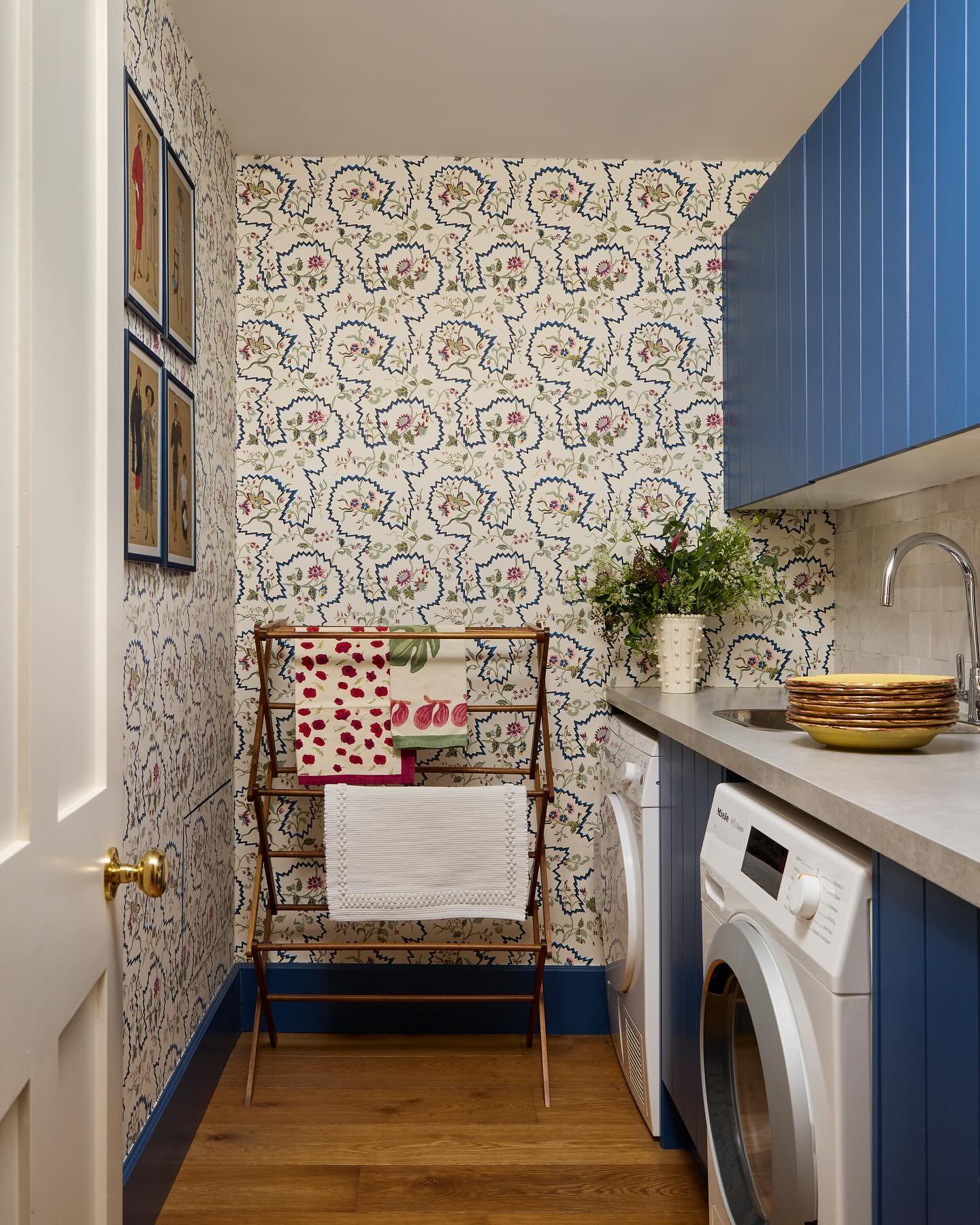 a cottage style laundry room with floral wallpaper and blue paint