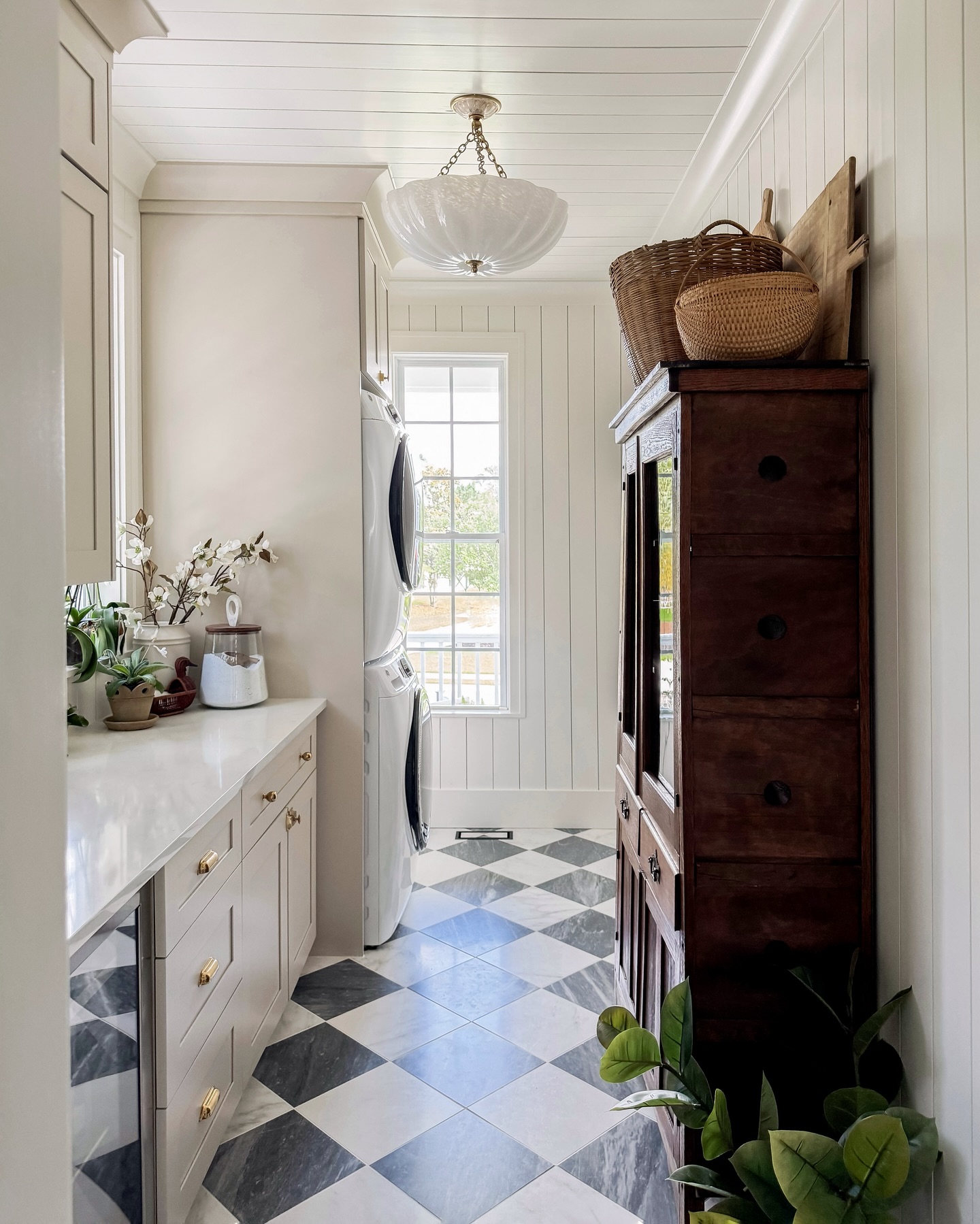 a cottage style laundry room with checkered tile and vintage furniture