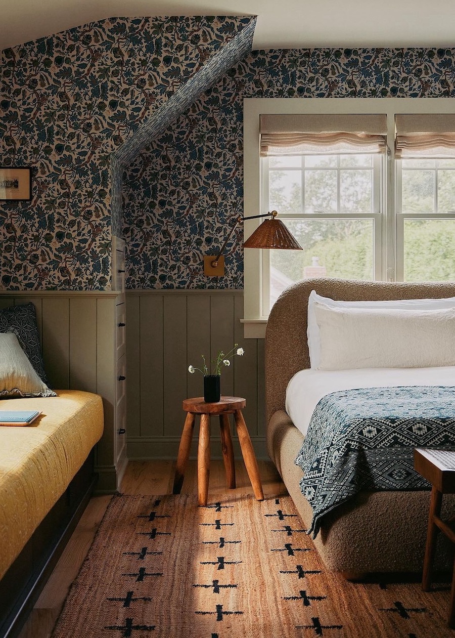 a cottagecore bedroom with blue floral wallpaper and vintage decor