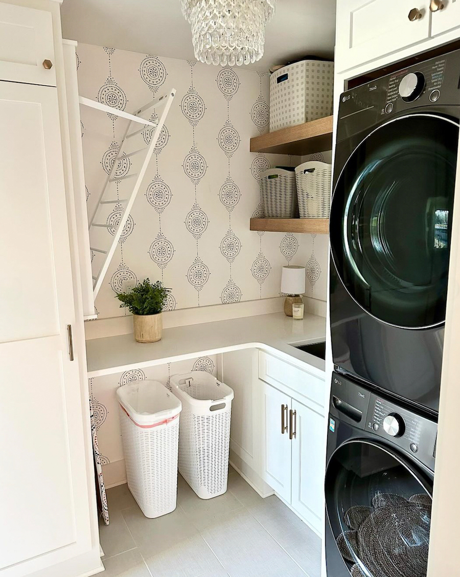 a small laundry room with a pull down drying rack, counters, and cabinets