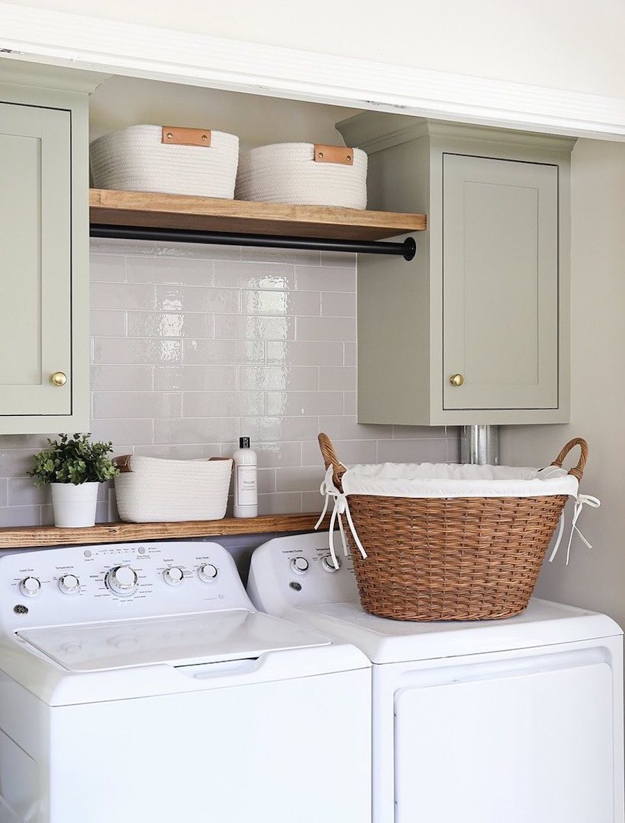 a small laundry room with upper cabinets and shelves