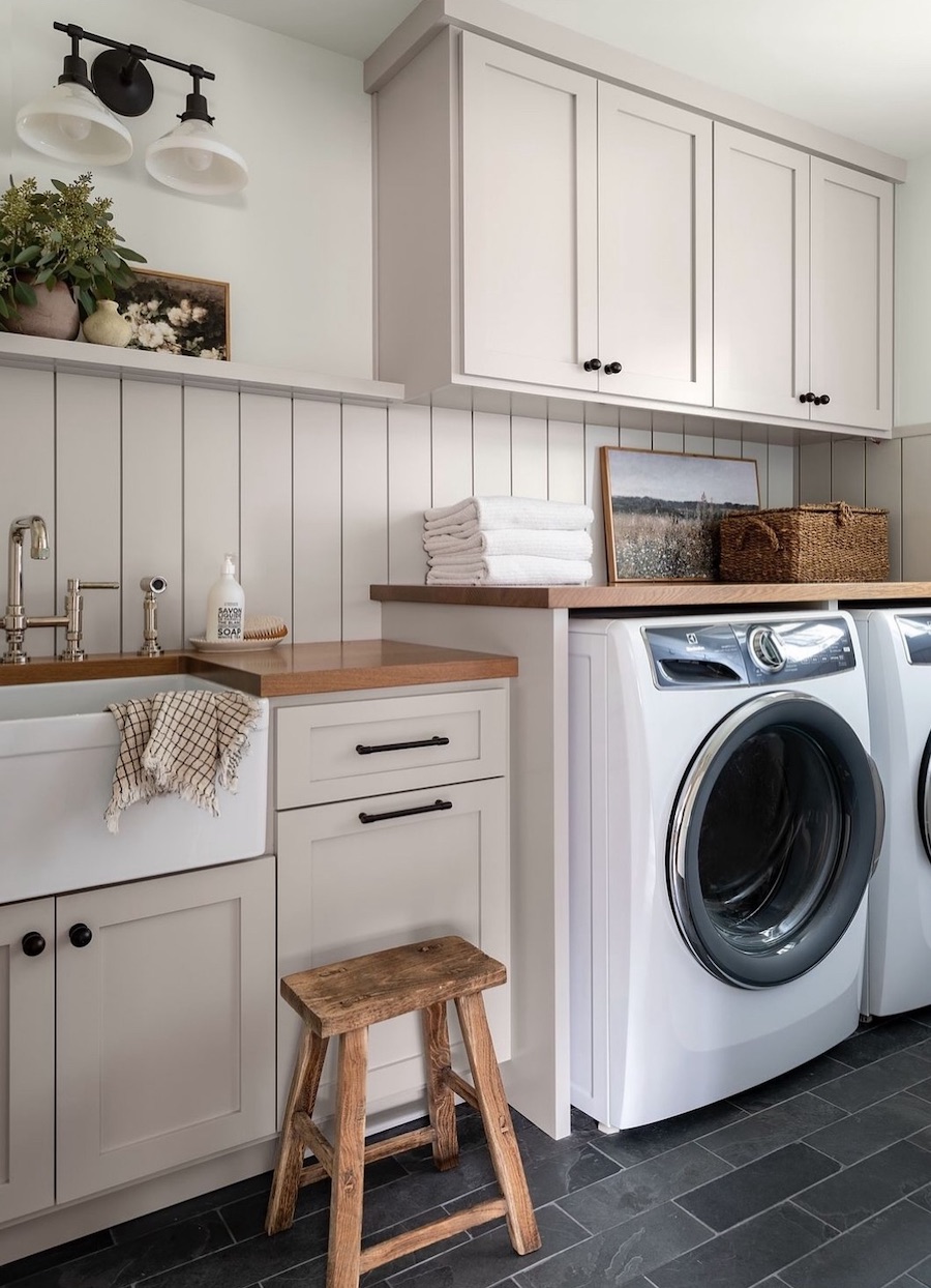 a small laundry room with wooden counters and cabinets