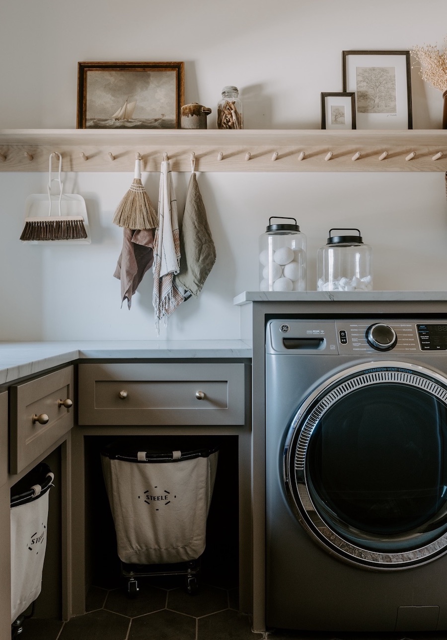 a small laundry room with cabinets, drawers, and upper shelves