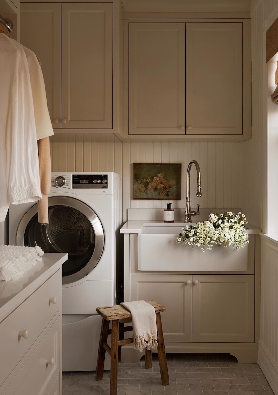 a small laundry room with upper and lower cabinets and a porcelain sink