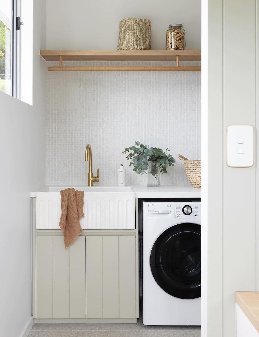 a small laundry room with open shelves, a porcelain sink, and countertops