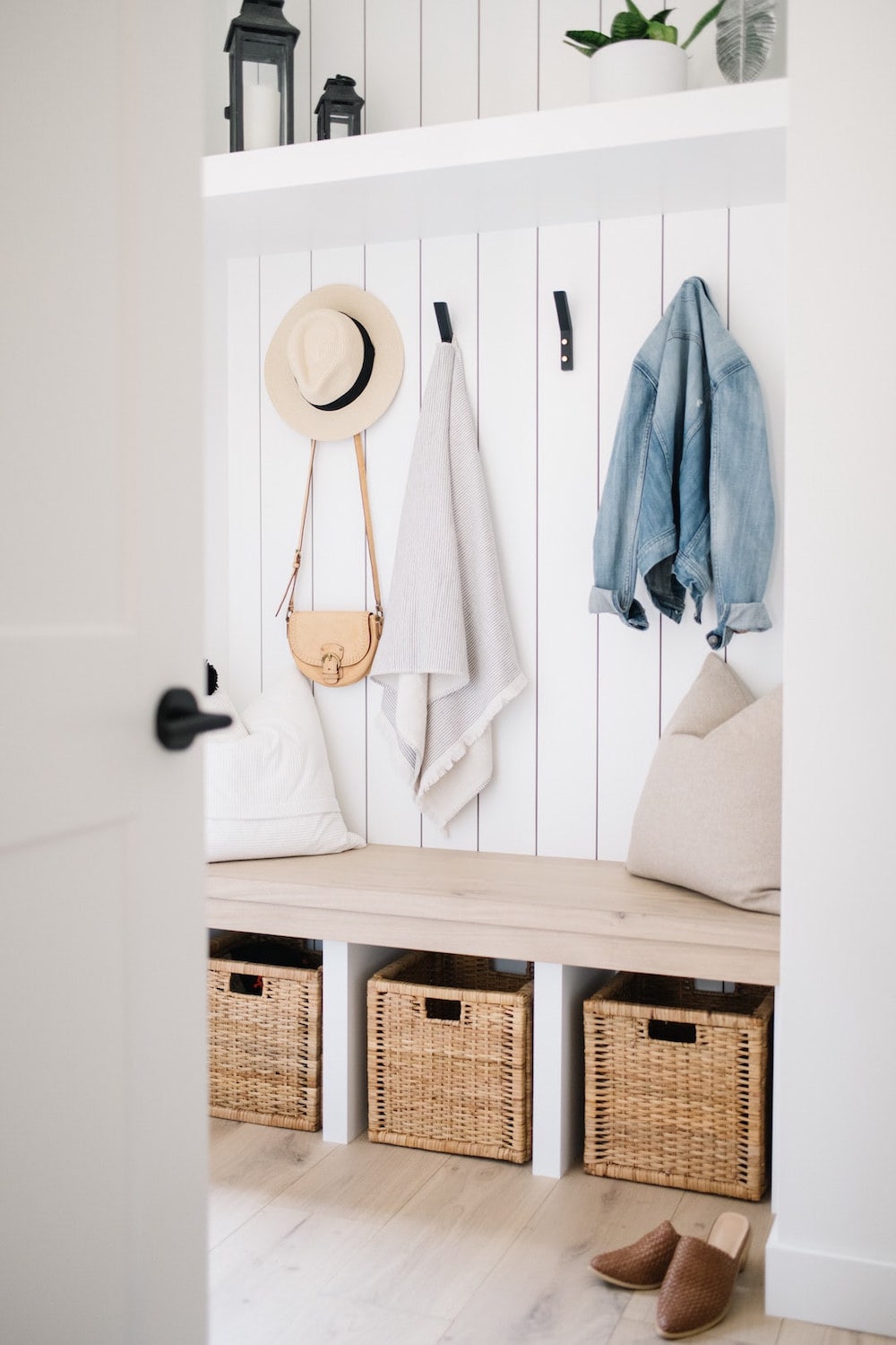 a white mudroom with shiplap walls, a bench, and storage for coats and shoes