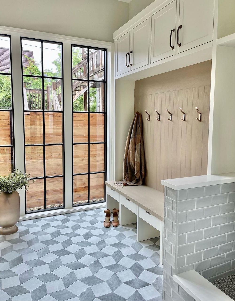 a mudroom with unique tiling, a bench, and storage for shoes and coats