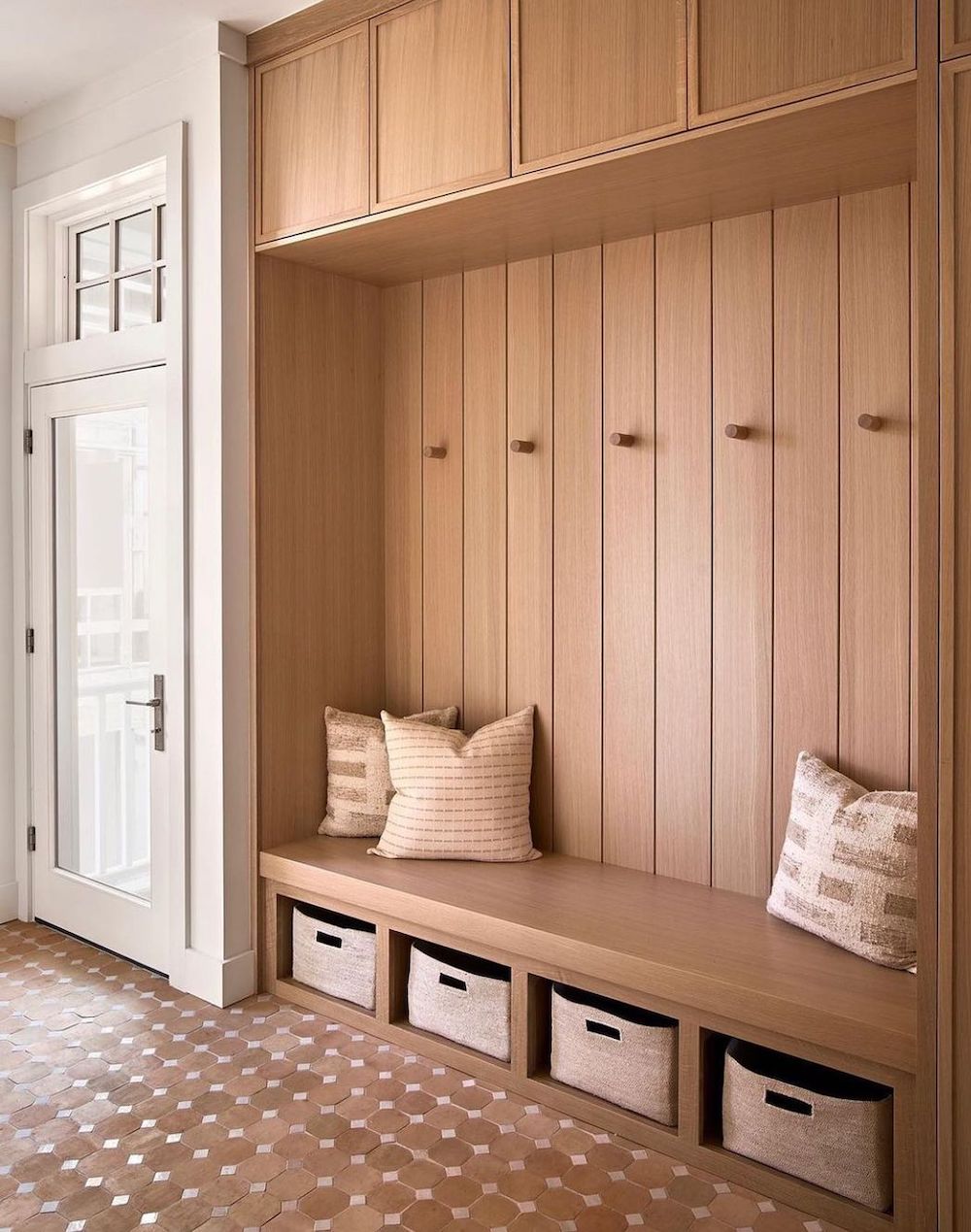 a mudroom with warm wood walls, a bench, and shoe and clothing storage