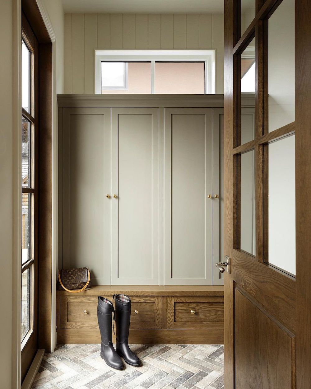 a mudroom with soft green walls and dark wood accents